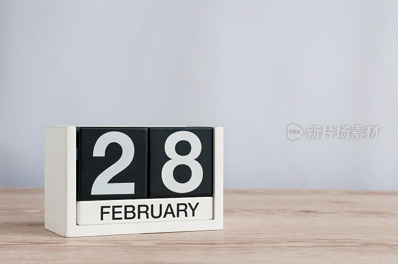 2月28日。2月28日的立方日历放在木桌上，留出文字空间。不是闰年或闰日