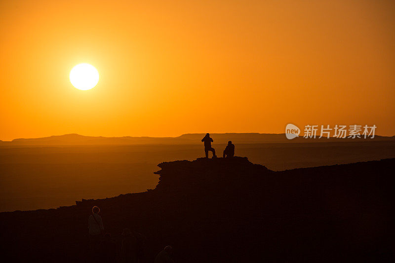 人们在沙漠山顶上看日落