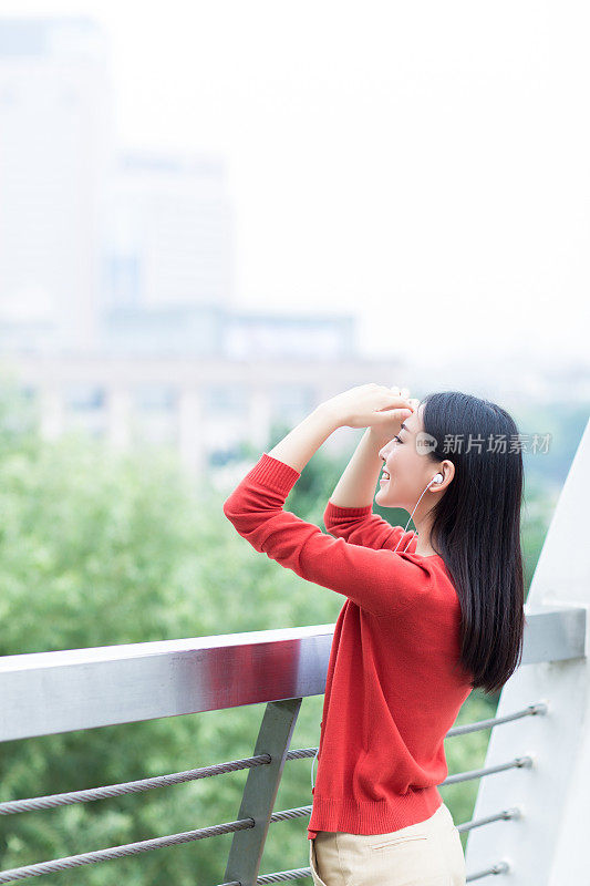 年轻女孩用智能手机的耳机听音乐