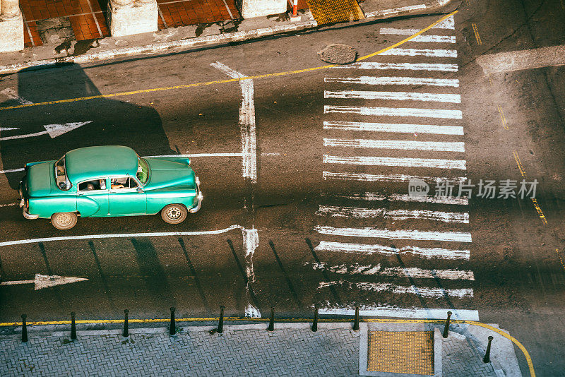 一辆绿色老爷车行驶在古巴哈瓦那的道路上