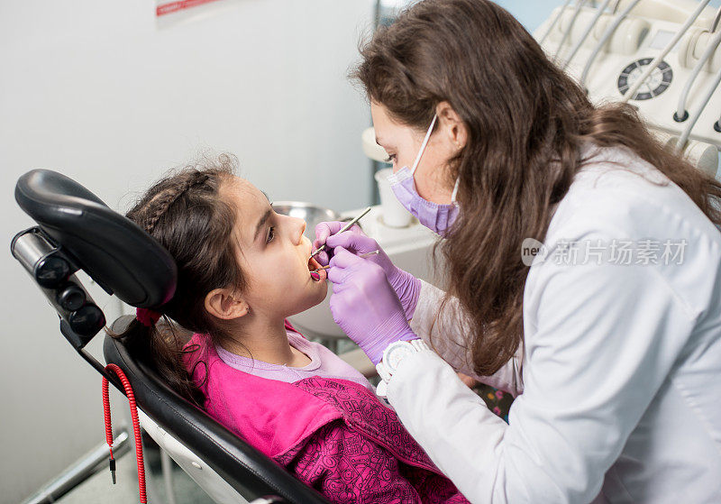 年轻的女牙医正在牙科诊所检查病人的牙齿。牙科