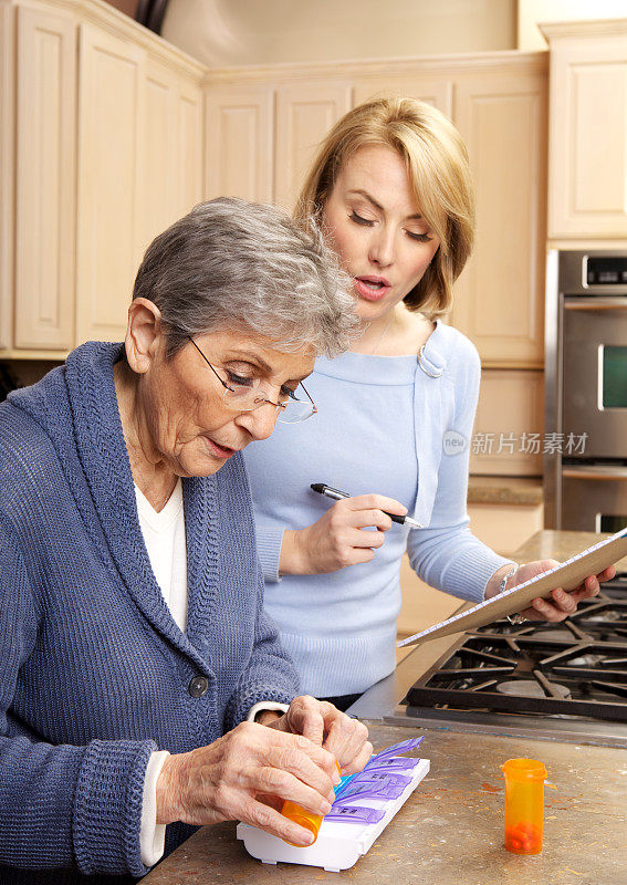 一个拿着写字板的女人在帮一个老女人整理药片