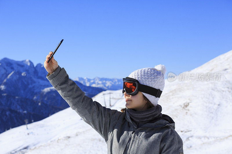 拍摄雪上滑雪的年轻女子自拍阿尔卑斯山