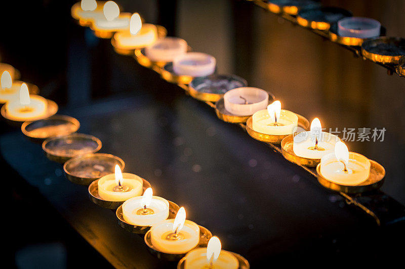 近距离的祈祷蜡烛在教堂的一排
