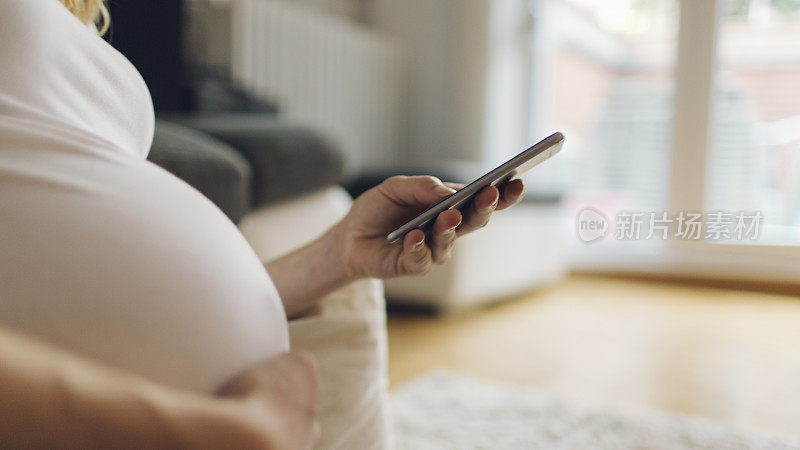 孕妇在智能手机上打字。