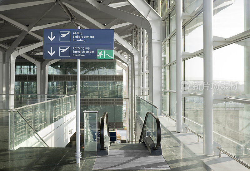 现代化的机场出发大厅，设有自动扶梯和玻璃窗