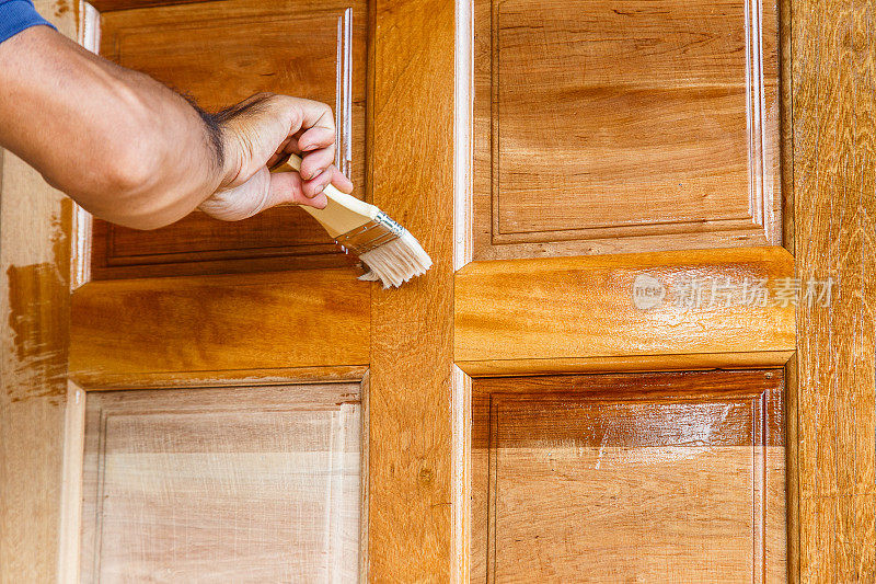 工人用油漆刷手绘木门，在木门上涂上亚麻籽油清漆
