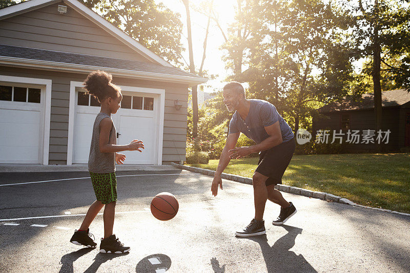 爸爸和儿子在家里的车道上打篮球