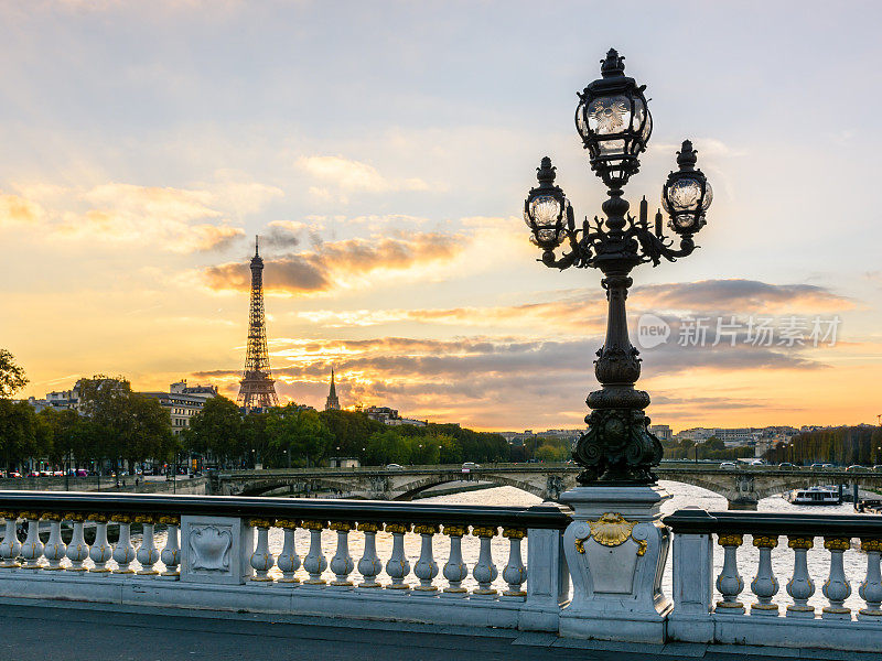 这是巴黎亚历山大三世桥上的一盏新艺术风格的路灯，夕阳西下时以埃菲尔铁塔为背景