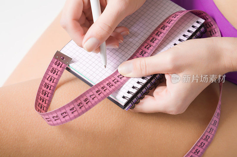 在训练前或训练后，女性在笔记本上写下锻炼计划、结果或其他文字。关心一具尸体。体育的概念。