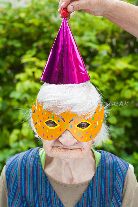 老妇人戴着五颜六色的面具和帽子庆祝