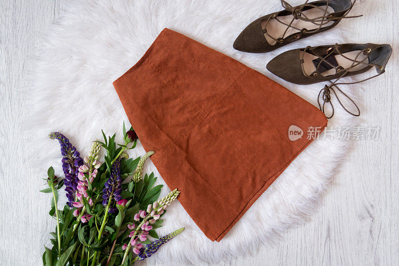 棕色麂皮裙和白色毛皮鞋，一束鲜花。时尚的概念