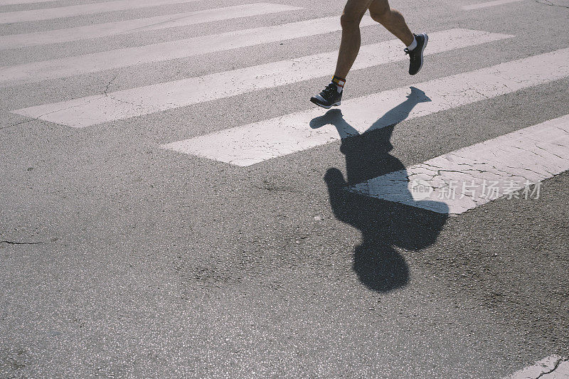 跑步者在街上慢跑，穿过人行横道