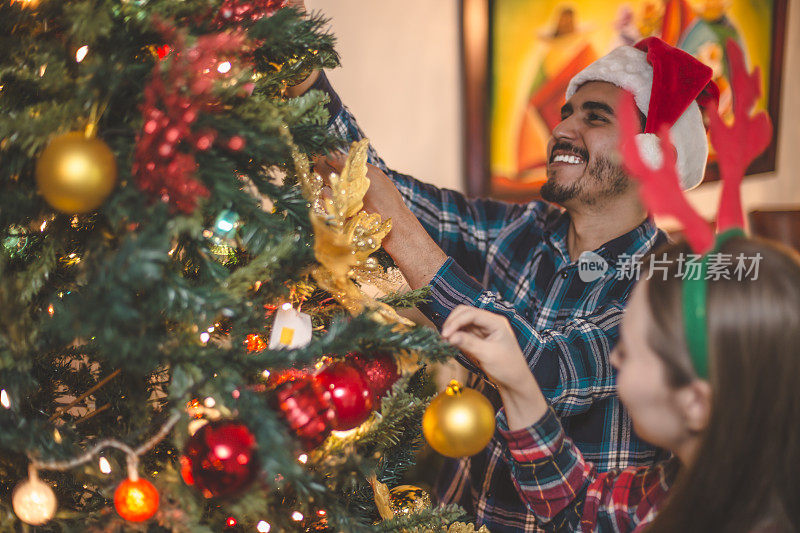 年轻夫妇帮助装饰圣诞树
