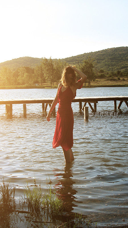 一个穿着红色裙子的女人站在湖里