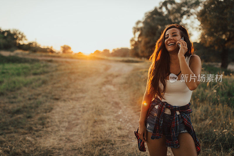 美丽的年轻女子在一个阳光明媚的日子在户外使用手机