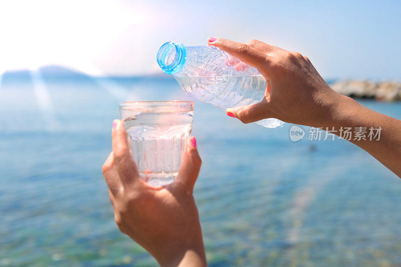 那只手正在把瓶子里的水倒在海滩上。