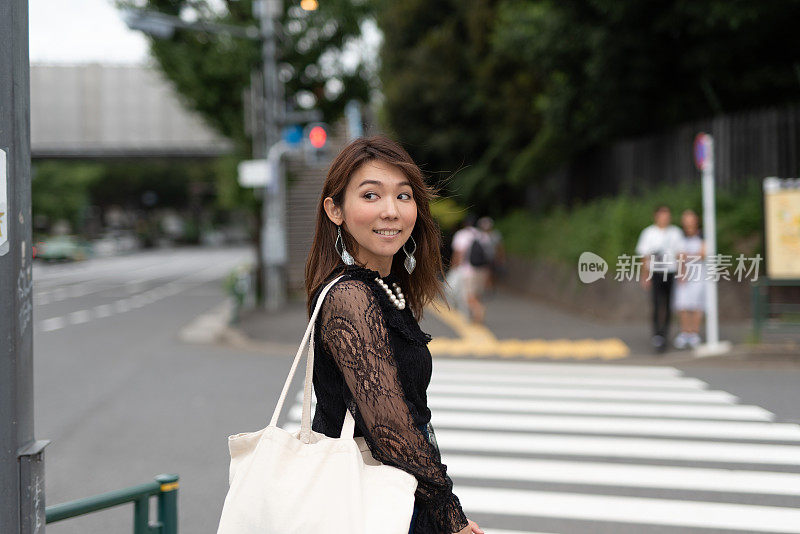 一名女子走在原宿车站附近的街道上，原宿是日本著名的观光胜地