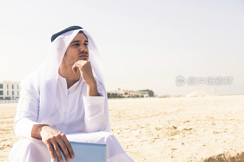 坐在海滩上的阿拉伯青年