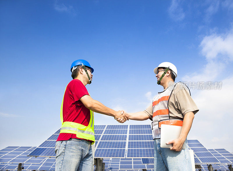 两名工人在太阳能发电站前握手