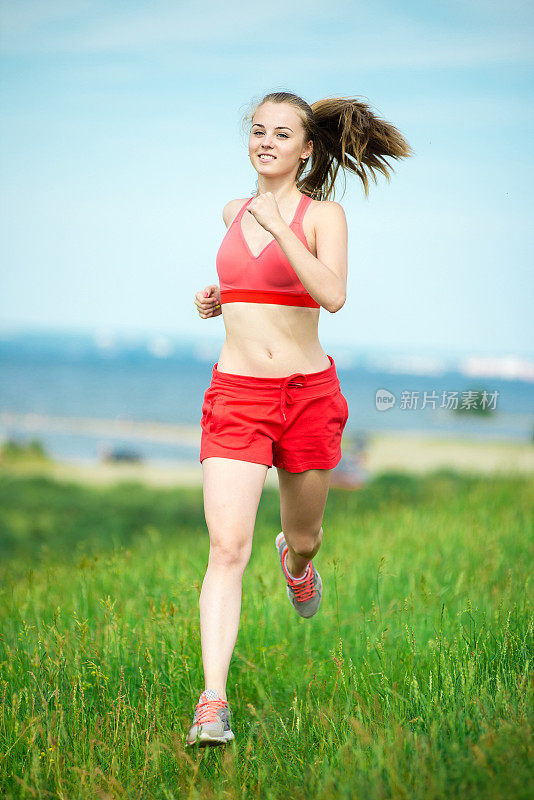 年轻女子跑着夏天公园乡村路。户外运动。J