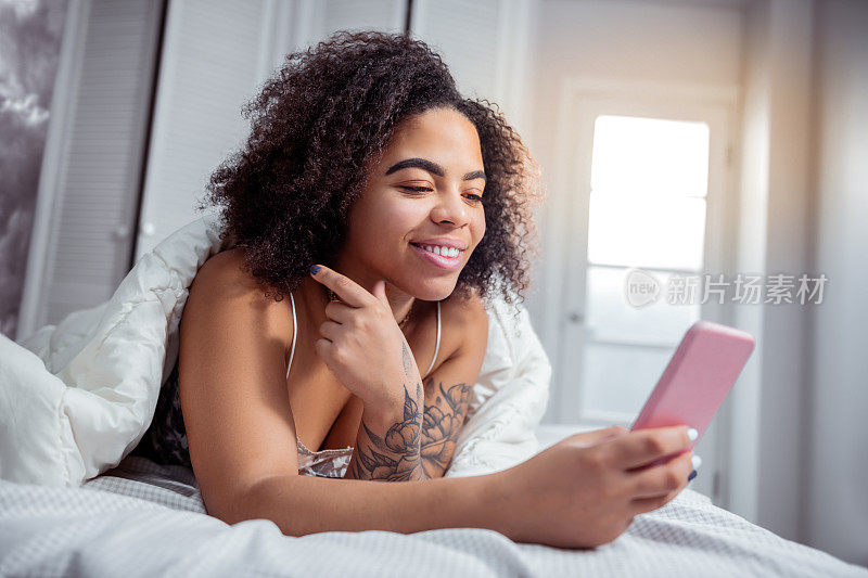笑容满面的非洲裔美国妇女在床上休息的早晨