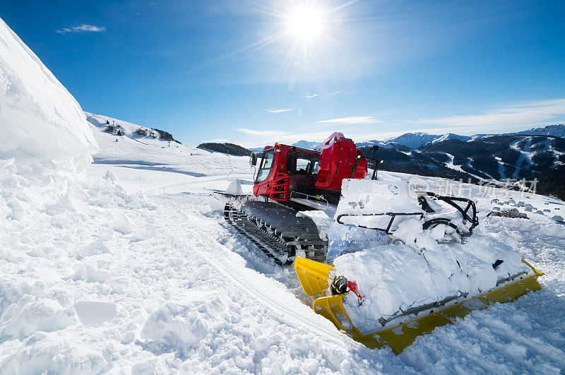 在一个阳光明媚的日子里，雪猫在滑雪道上清理积雪