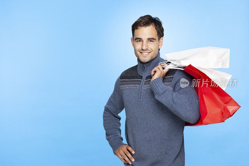 满意的购物男子肩上扛着购物纸袋。冬天的圣诞节。