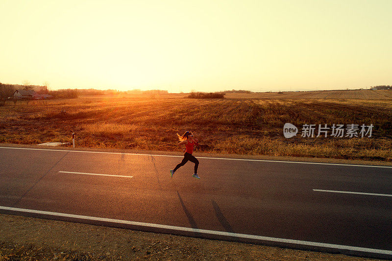 女运动员在日落时在马路上奔跑