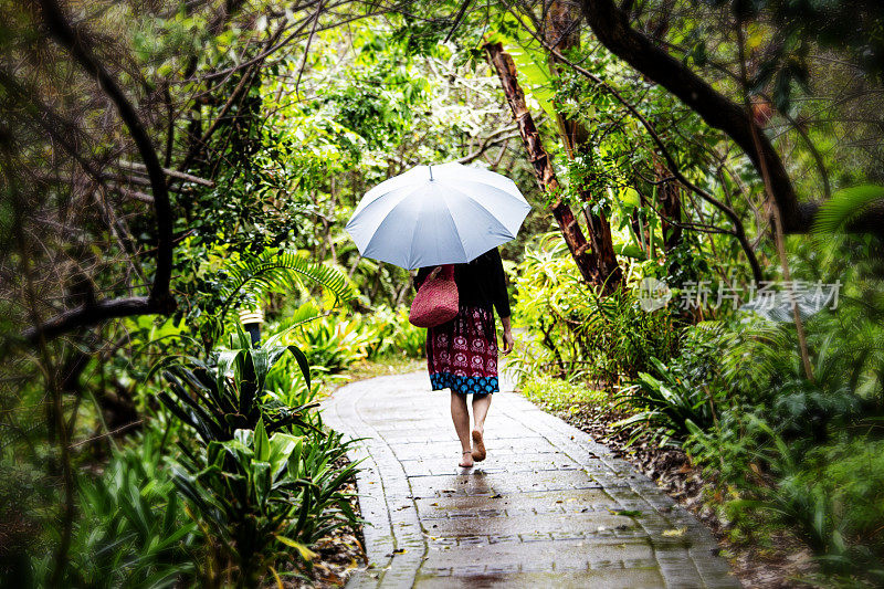 雨中，一个女人独自走在一条砖路上