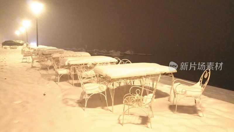 桌子和椅子在晚上覆盖着雪