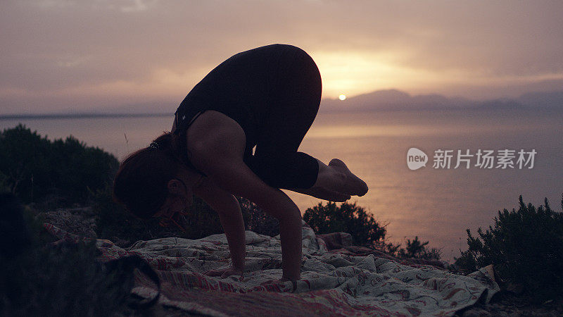 保持乌鸦式的平衡。在海岸线上做瑜伽的女人
