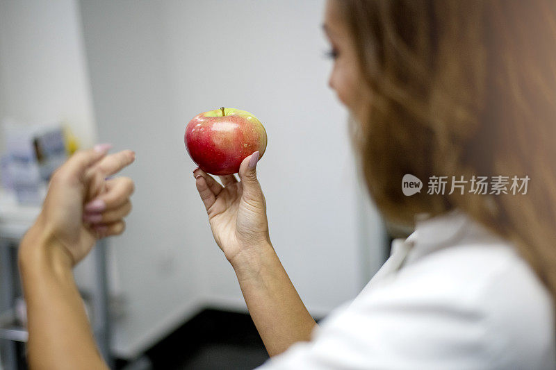 看牙医的女人手里拿着红苹果