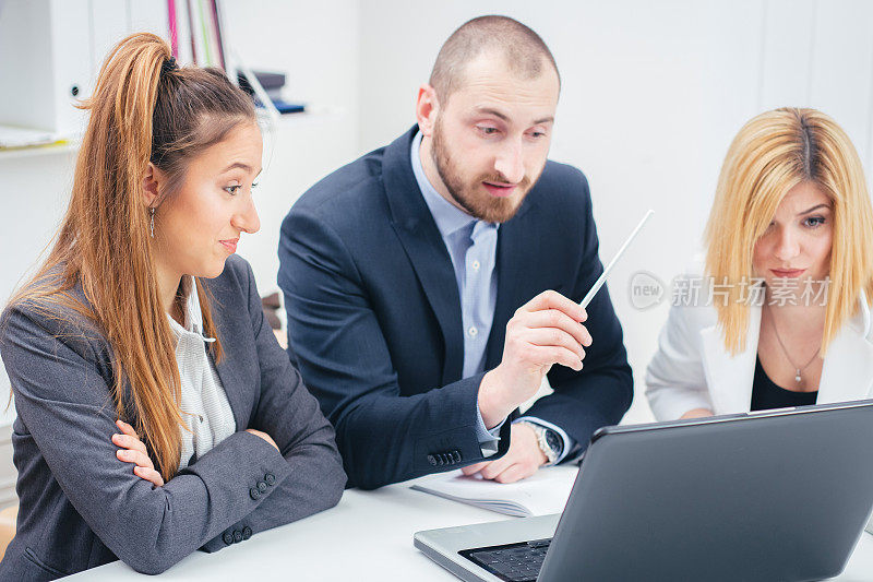 三个年轻的商人坐在会议室的办公室里讨论他们正在进行的项目。