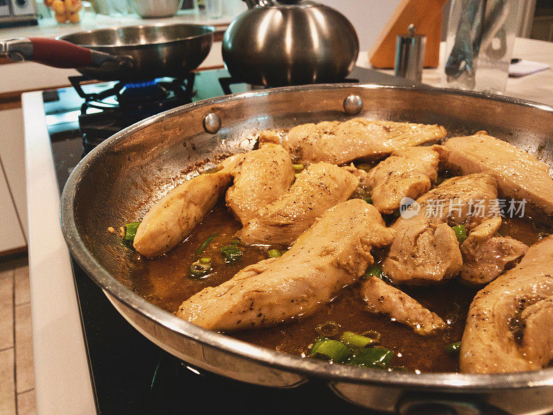 烹饪柠檬鸡类食物，在煤气炉上用不锈钢平底锅烹饪