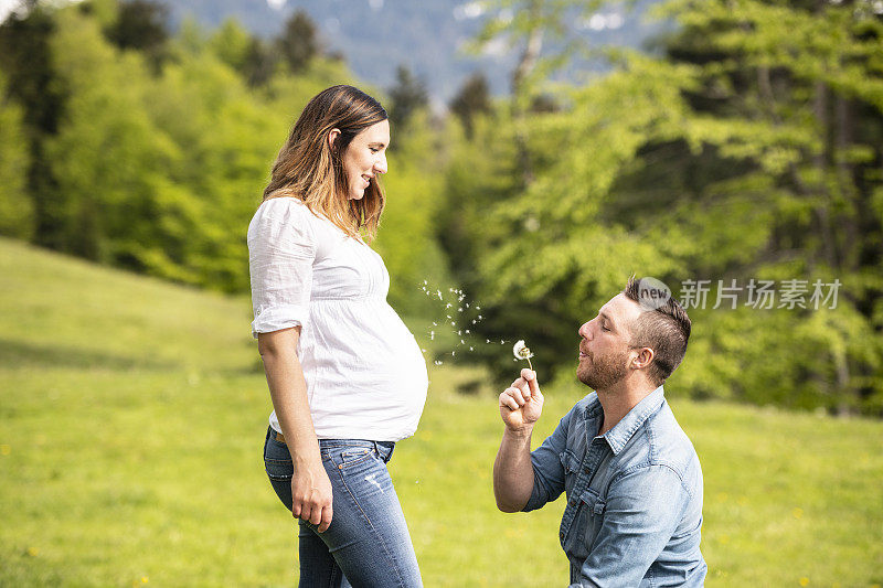 微笑的男人跪在他怀孕的女友面前