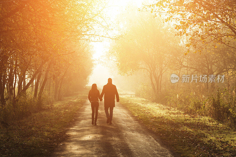 一对年轻夫妇漫步在秋日的阳光下