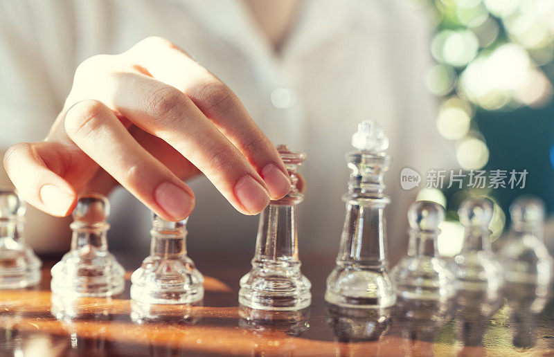一位女商人双手紧握，在一张旧木桌上谋划下棋的策略。