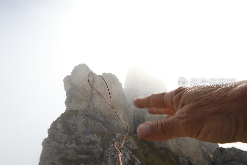 登山者把绳子扔到岩石顶峰