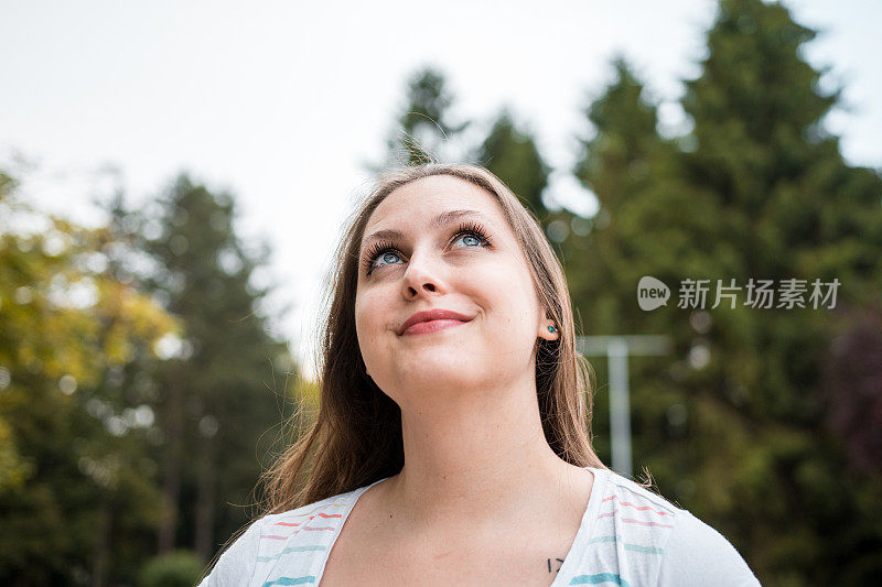 一个年轻漂亮的棕色头发的女人的肖像环顾她的户外