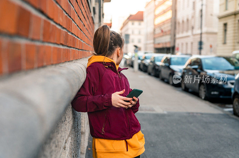 一个小女孩在城市的街道上用手机