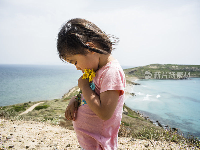 多愁善感的小女孩在海的背景中捧花