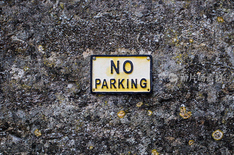 古老的“禁止停车”标志上风化的老石头纹理的墙壁