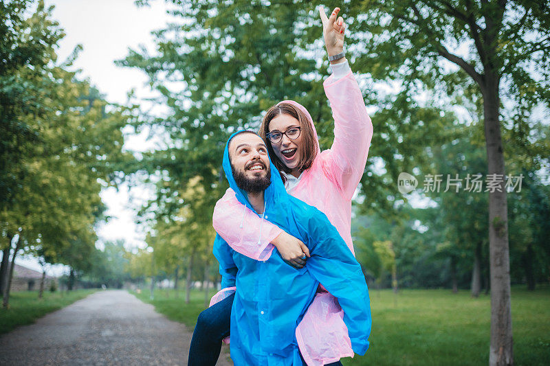 幸福的年轻夫妇穿着雨衣，在大自然中玩得很开心。