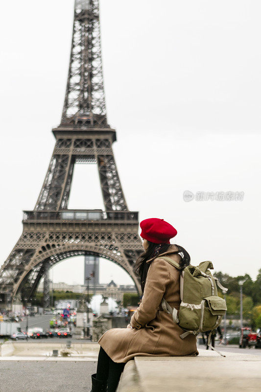 亚洲旅行者坐在巴黎的埃菲尔铁塔