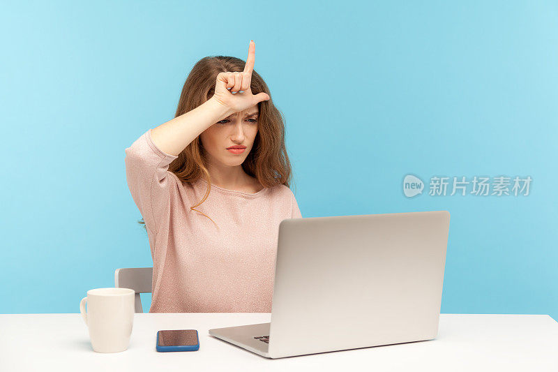 失去了工作。悲伤沮丧的年轻女子向笔记本电脑屏幕展示失败者的手势，在视频电话中讲述她被解雇的经历
