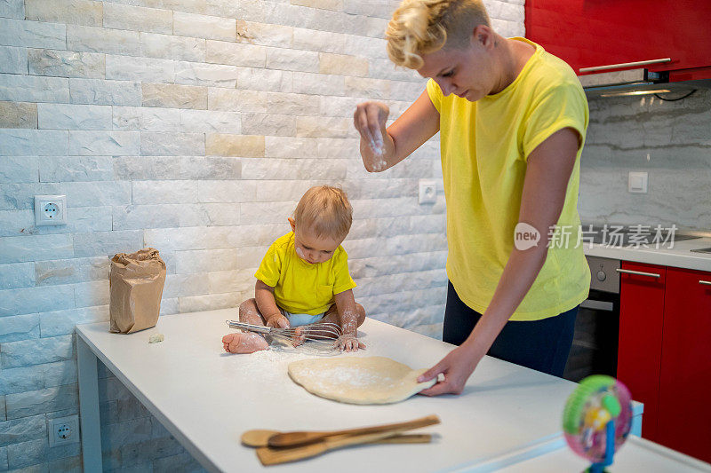 妈妈和她的儿子正在一间明亮的厨房里做饭。孩子帮父母揉面团烘焙。鬼混，把钱弄脏。