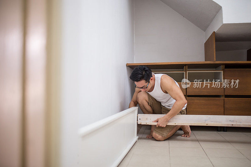 一个成熟的亚洲男人正在安装家具。