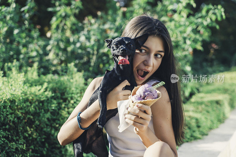 十几岁的女孩遛着狗吃着冰淇淋。