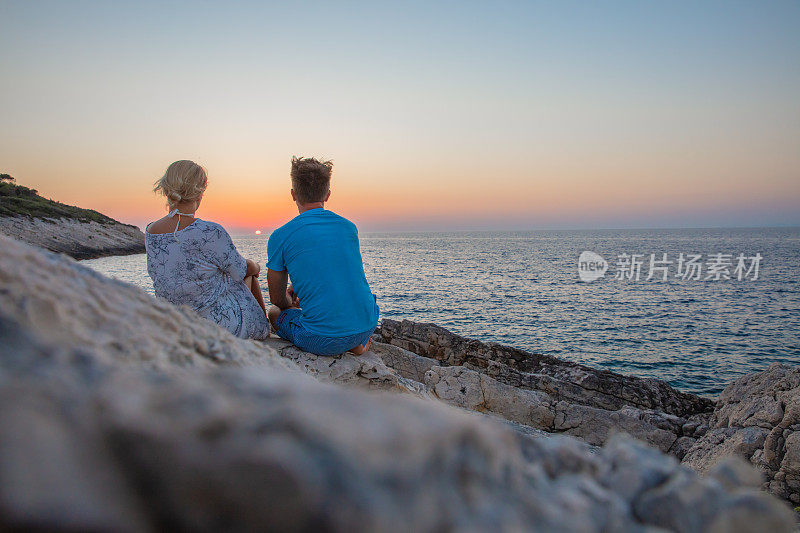 一对夫妇在克罗地亚亚得里亚海的海边欣赏日落